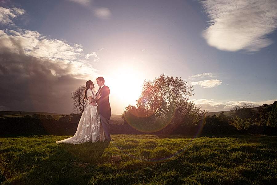 A couple embracing in a sunlit field at sunset captured by a North East Wedding Photographer.